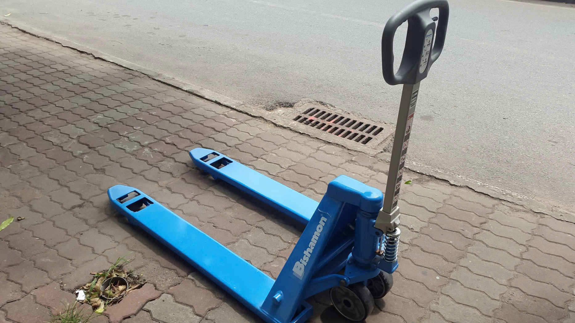 Xe nâng tay Bishamon màu xanh dùng di chuyển pallet trên nền gạch ngoài trời